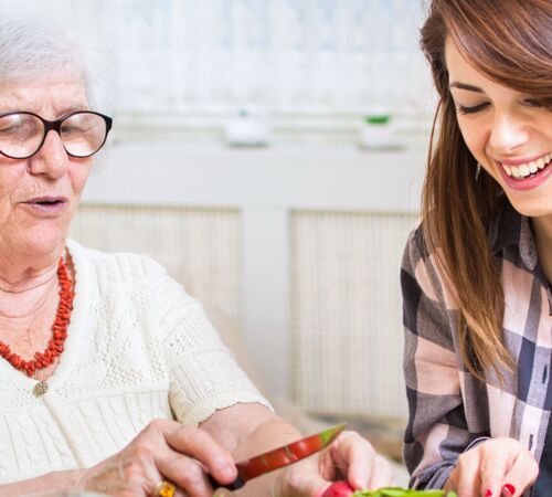 Seniorin mit junger Frau beim Kochen