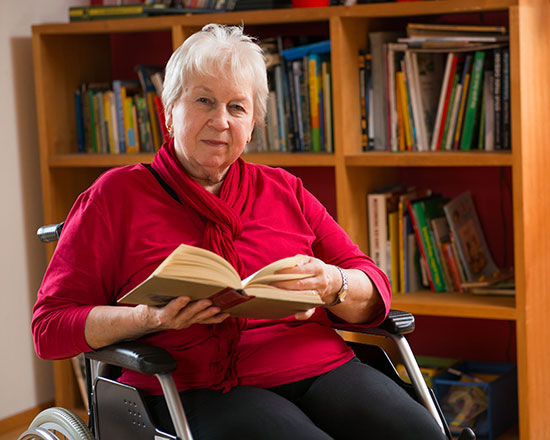 Seniorin im Rollstuhl liest ein Buch